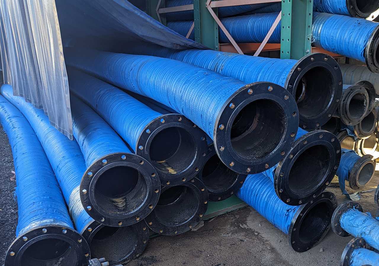 Slurry hose with ANSI flanges piled up, stored outside