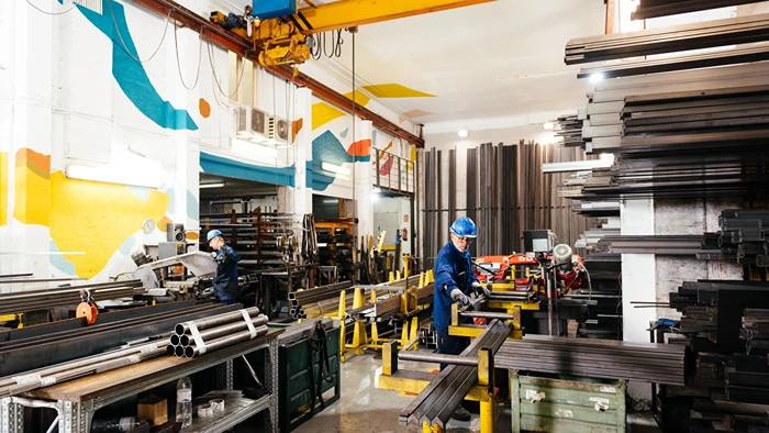 Industrial steel manufacturing workshop featuring workers handling metal products