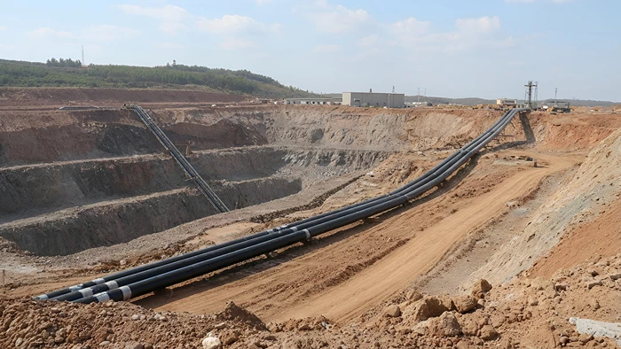 Excavated mining area showing pipeline layout for industrial fluid transport