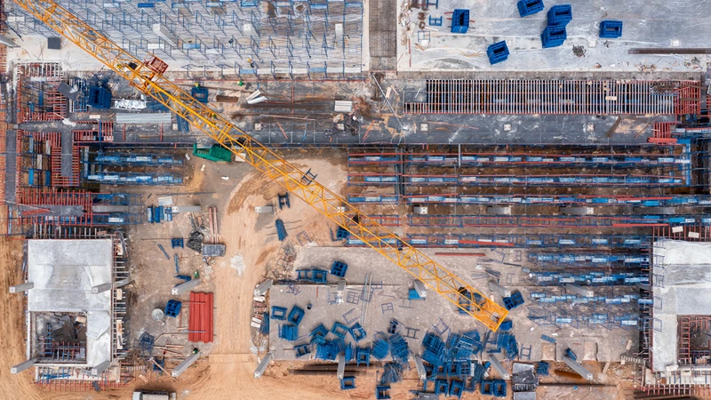 Aerial view of a large construction site with heavy machinery and a yellow tower crane