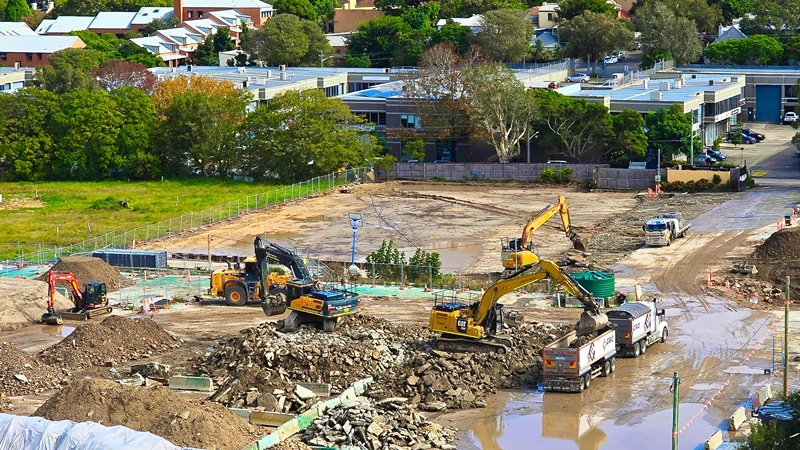 Construction site with heavy machinery performing earthworks and soil leveling